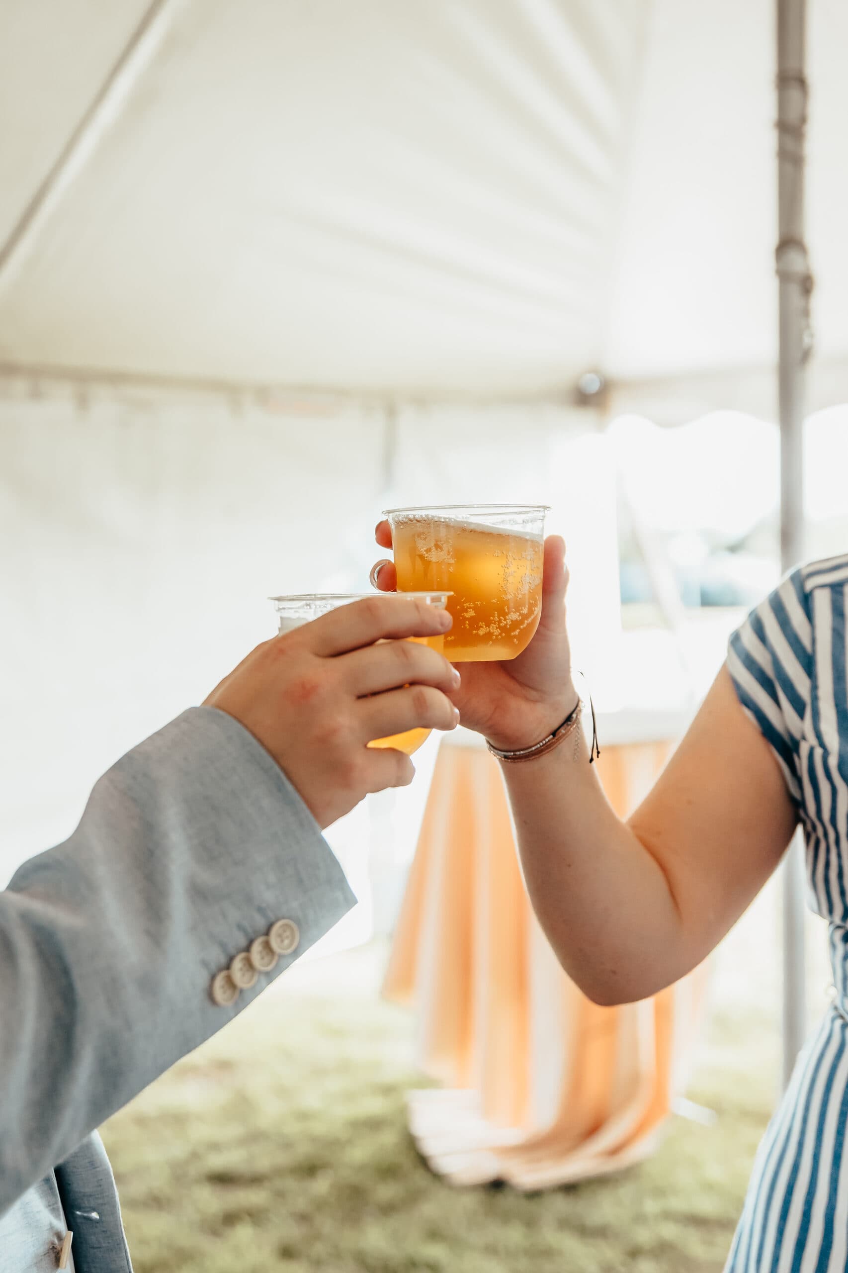 Guests toasting cocktails under the tent